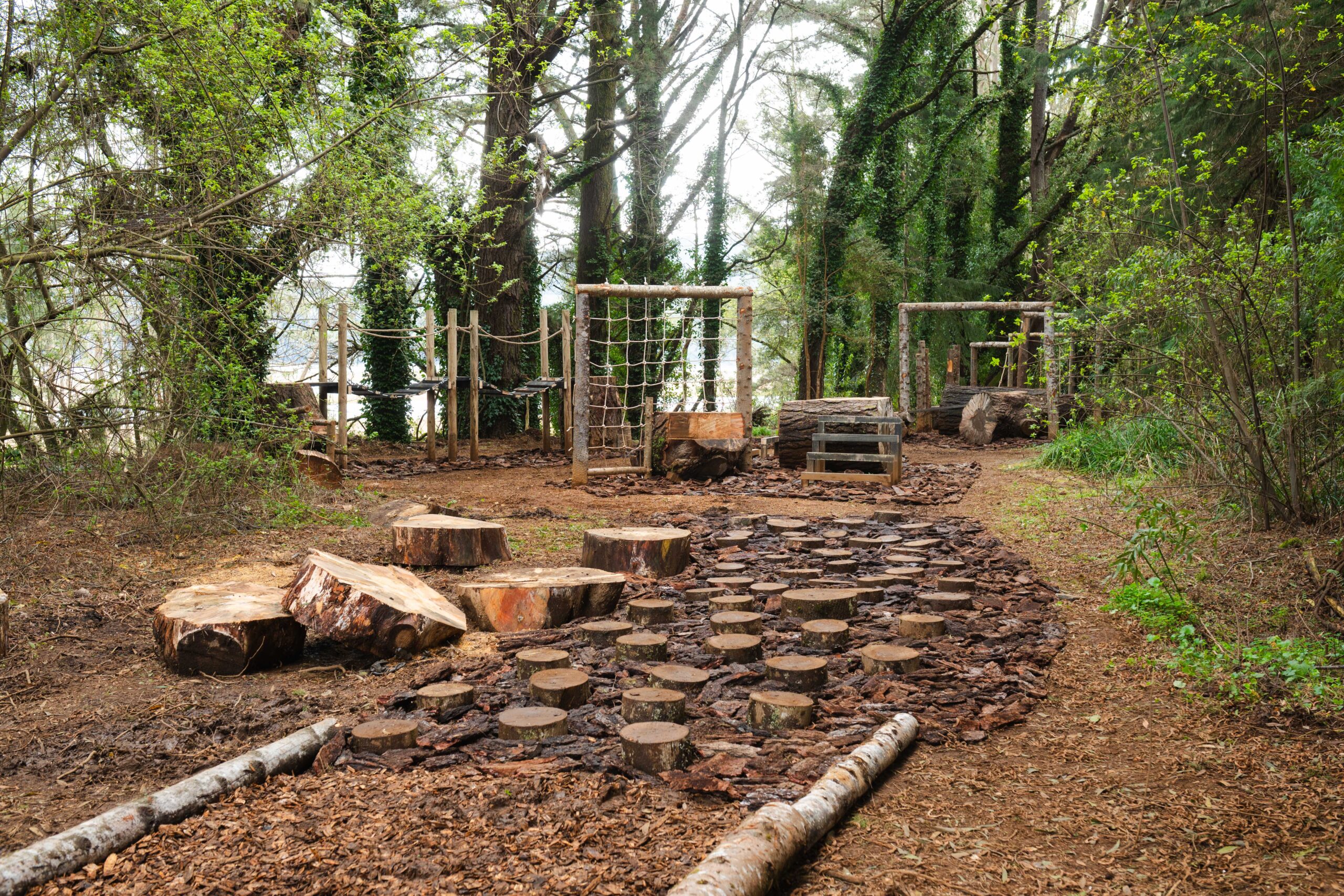Estaciones de desafío del Sendero del Explorador, con troncos, puente de cuerdas y estructuras de madera en el bosque de Puerta del Sur